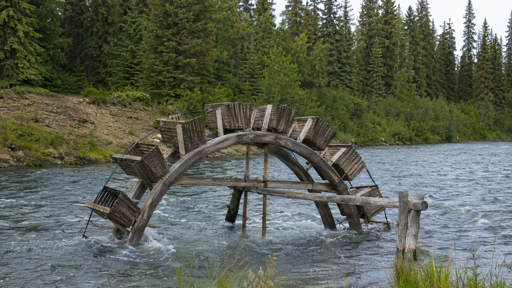 Traditional wooden fish wheel with rotating baskets installed on an Alaskan river